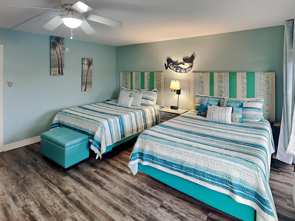 two beds in a bedroom with blue walls and wooden floors at Laguna Reef #121 - Gone Coastal in Rockport