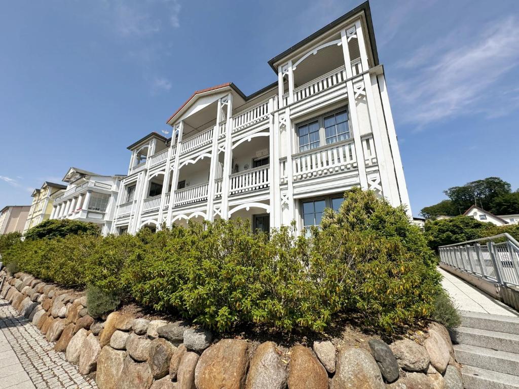 a large white building with a stone wall at Villa Annika - Whg 06 in Ostseebad Sellin