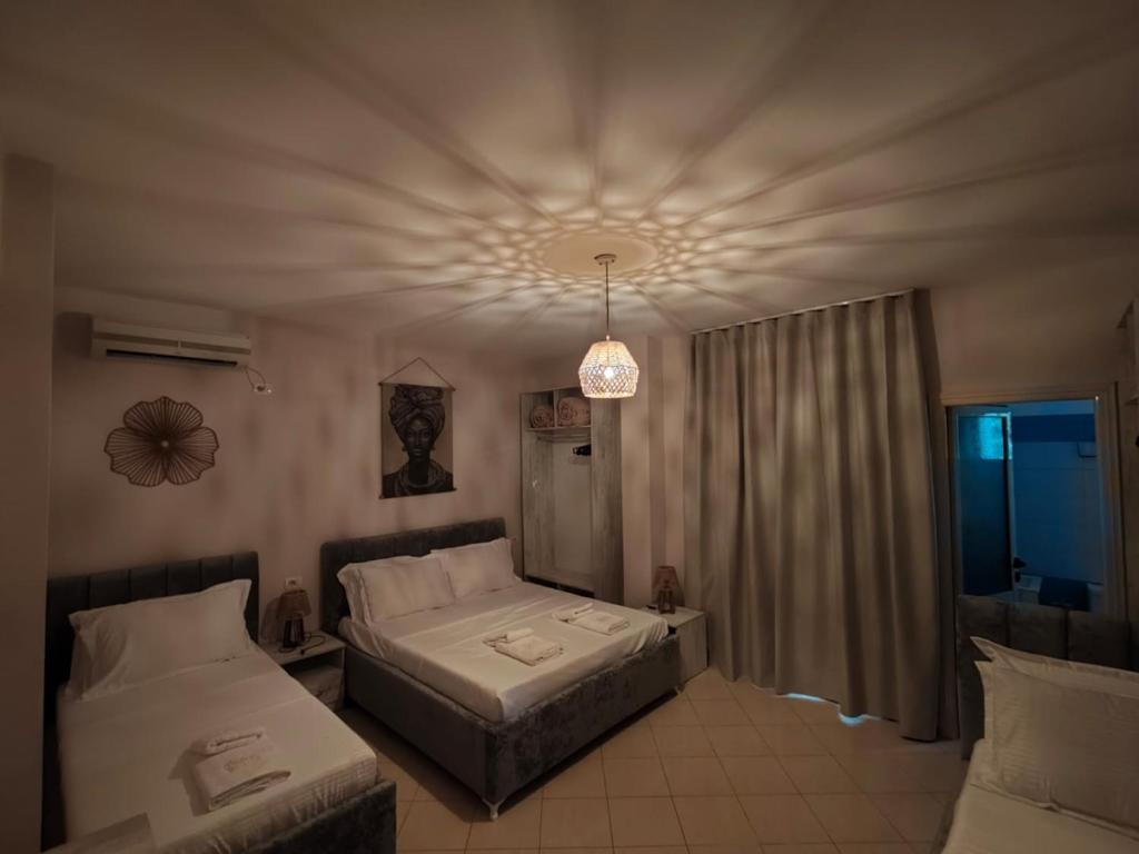 a bedroom with two beds and a chandelier at Hotel Natali 2 in Dhërmi
