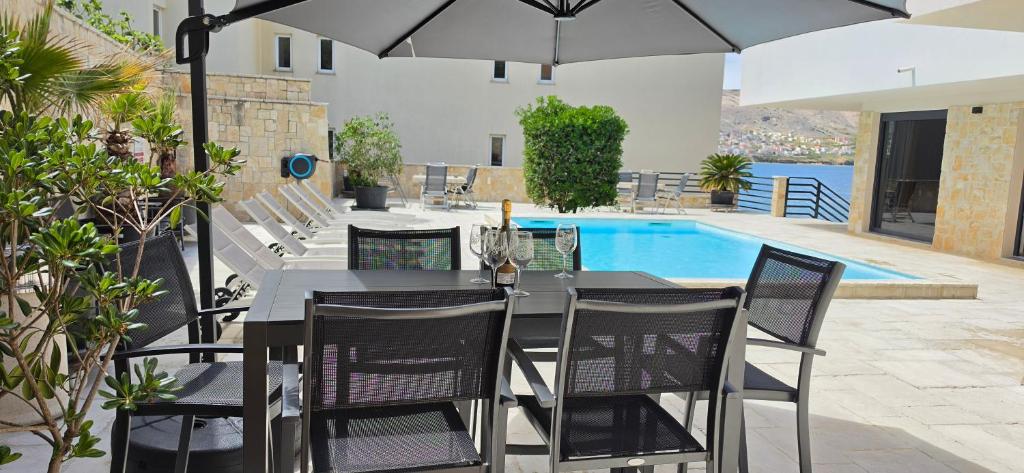 a dining table with chairs and an umbrella on a patio at Villa Kajgo-Pag in Pag