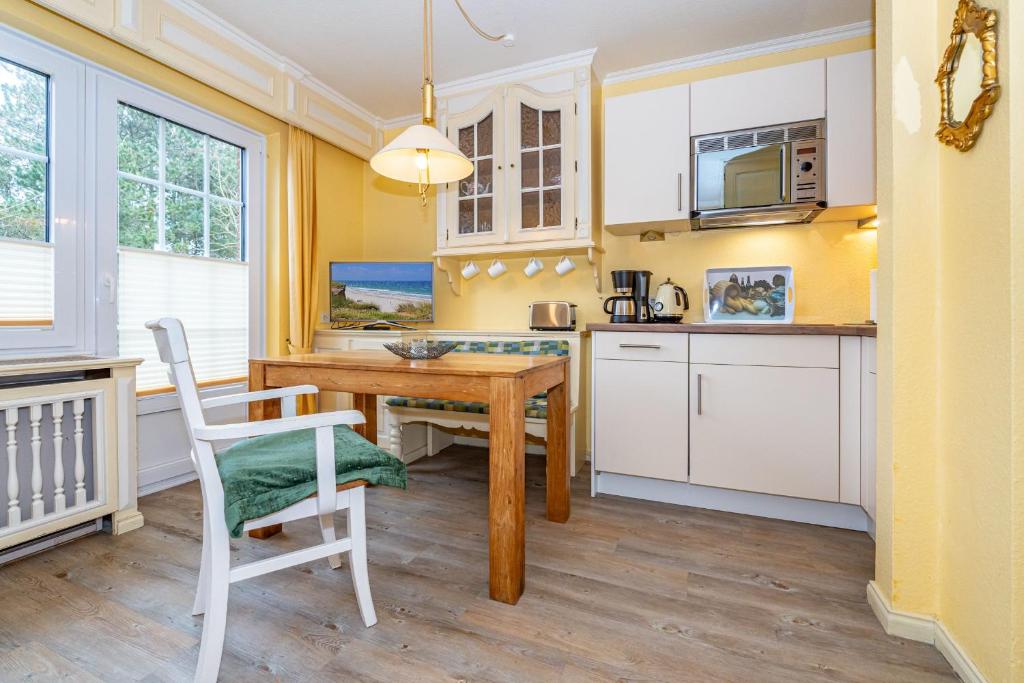 a kitchen with white cabinets and a wooden table and chairs at Priel-Hüs in List