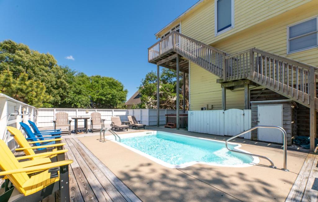 a swimming pool with chairs and a house at Shore is Fun - Duck, Poteskeet, Beach 480 Yds, 3 Min. Walk to Downtown, Pool, Hot Tub, YR Flex in Duck