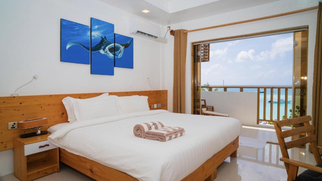 a bedroom with a bed with a view of the ocean at Luau Beach Inn, Maldives in Fulidhoo