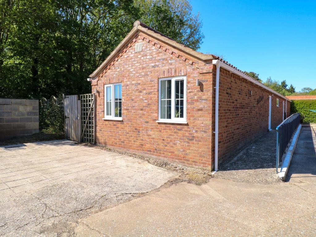 a brick building with a gate and a fence at Mill Lodge in Brisley