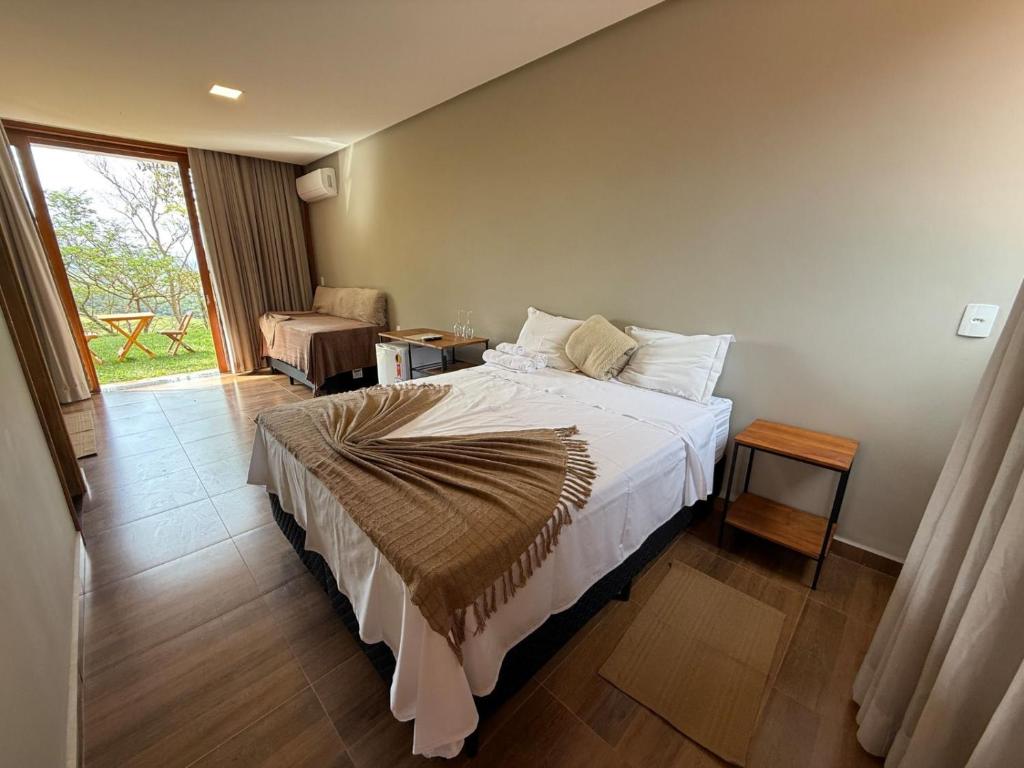 a bedroom with a large bed and a window at Pousada Carraro in Delfinópolis