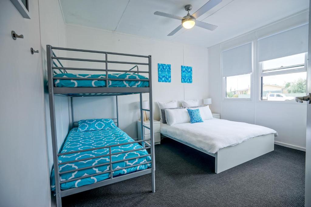 a bedroom with two bunk beds and a ceiling fan at Breakaway Moonta Bay in Port Moonta