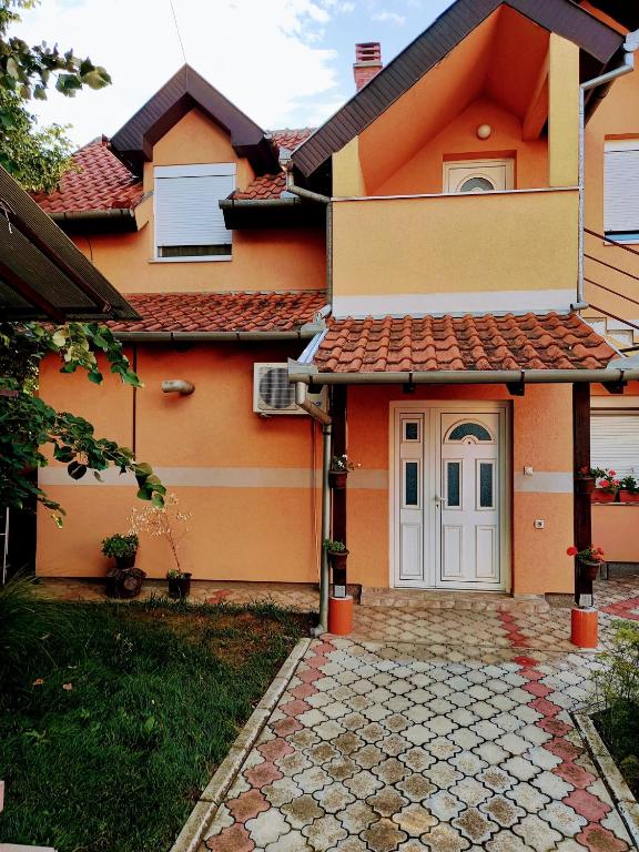 a orange house with a white door and a yard at Stan na dan J & M in Vršac