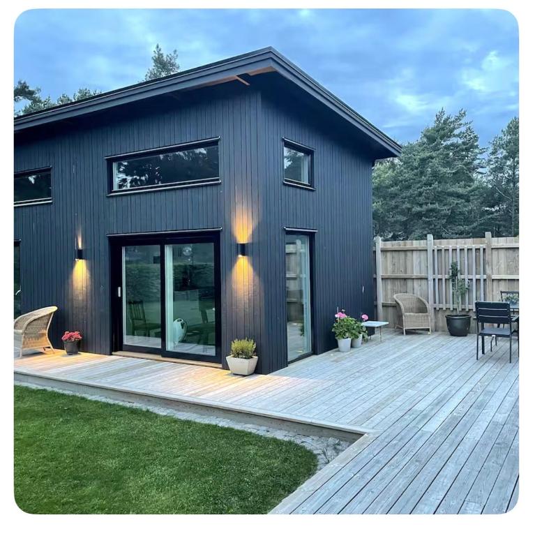 a black house with a deck and a patio at Seabreeze Pine Retreat in Åhus