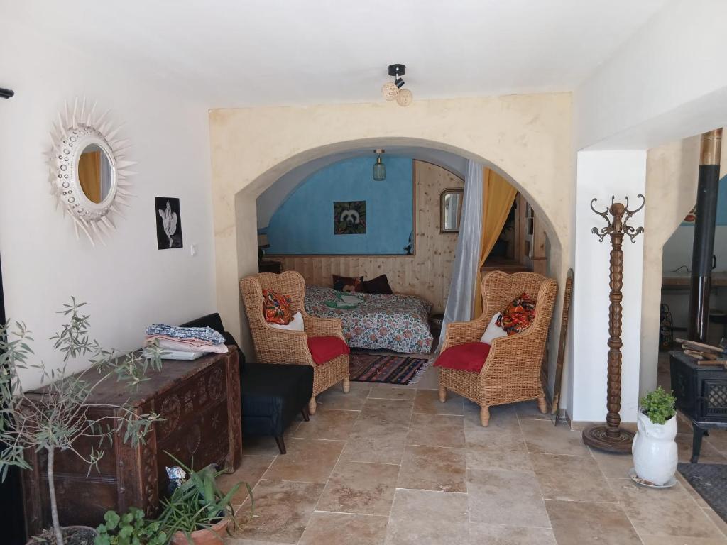 a living room with a bed and wicker chairs at Gite Le Romanesque in Clelles