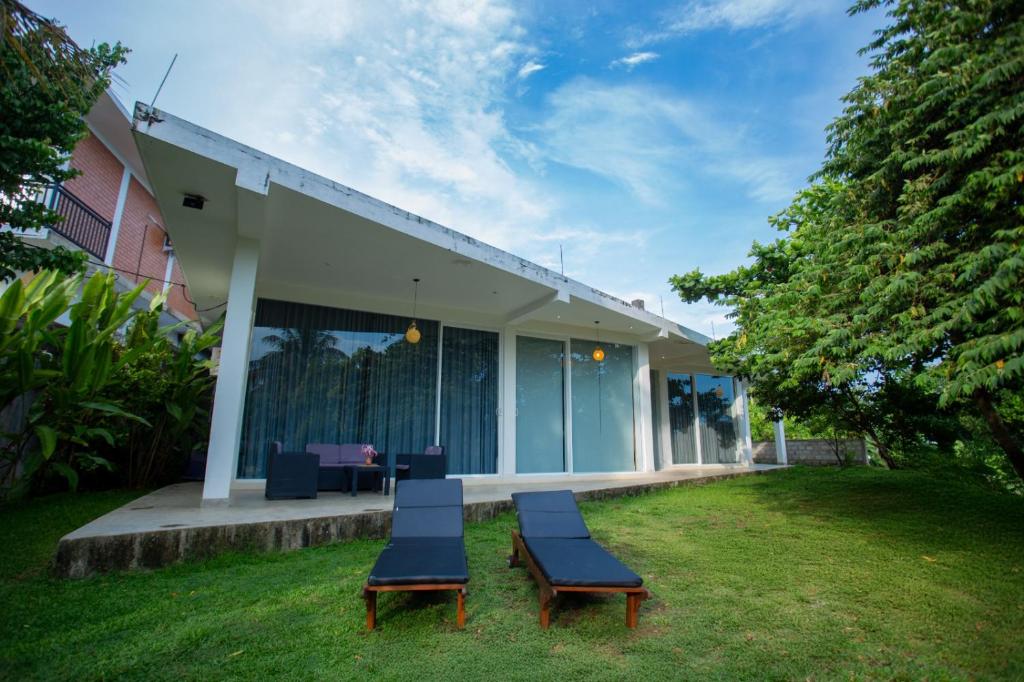 a group of chairs sitting on the grass in front of a house at Sudu Appu Villa Beruwala in Beruwala