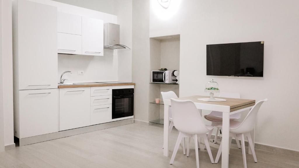 a white kitchen with a table and white chairs at Maison La Chicca in Molfetta