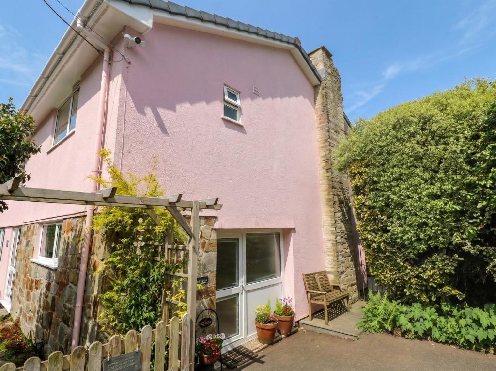 a pink house with a wooden fence at Mini Mena in St Austell