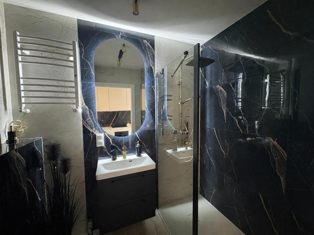 a bathroom with a sink and a mirror at Augustowskie Apartamenty Blisko Jezior i Lasów oraz Bezpłatny parking in Augustów