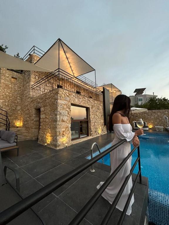a woman standing on a balcony next to a swimming pool at Beit el loz in Ghazīr