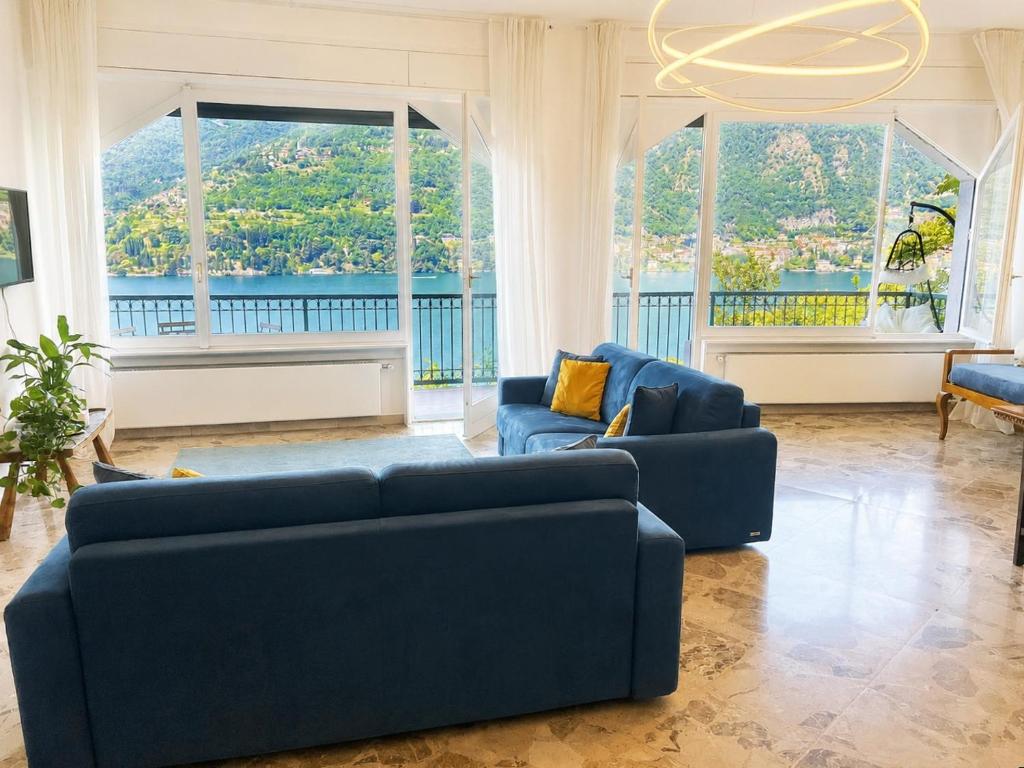 a living room with two blue couches and large windows at Botanic Garden Lake Como in Blevio