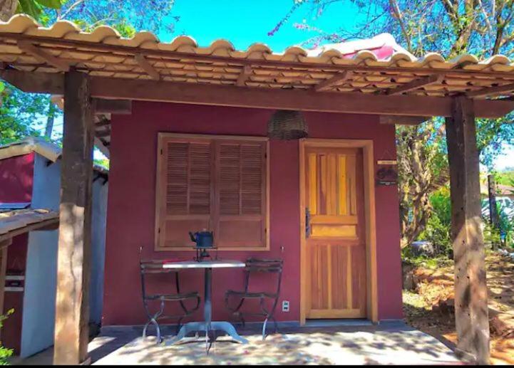 a red house with a table and chairs in front of it at Chalé da Serra in Brumadinho