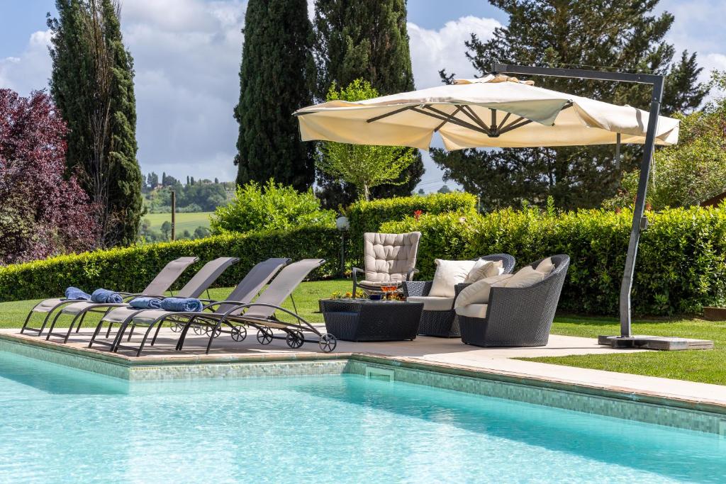 a group of chairs and an umbrella next to a swimming pool at Villa Sabrina by PosarelliVillas in San Gimignano