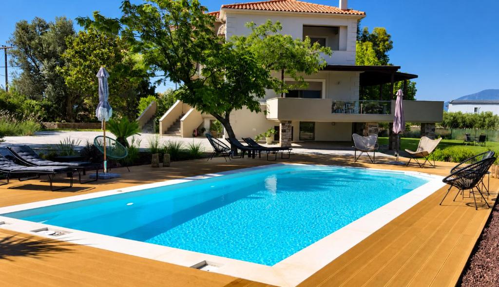 a swimming pool with chairs and a house in the background at Villa Polyxeni Lavender 150m from the sea in Politika