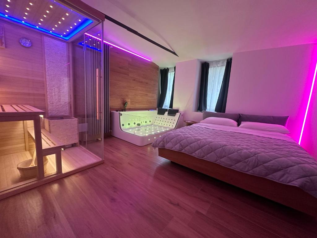 a bedroom with a bed and a tub with purple lights at Romantic Spa del Lago in Viverone