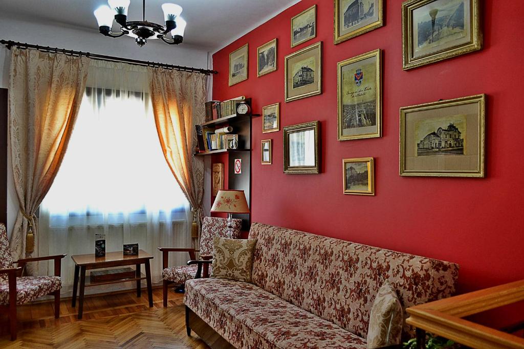 a living room with a couch and a red wall at Casa Nobilium in Turda