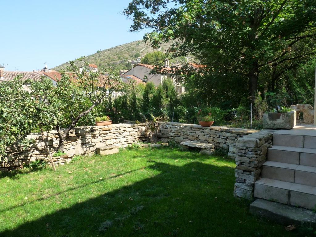 a garden with a stone retaining wall and a tree at Oustalou in Saint-Rome-de-Tarn