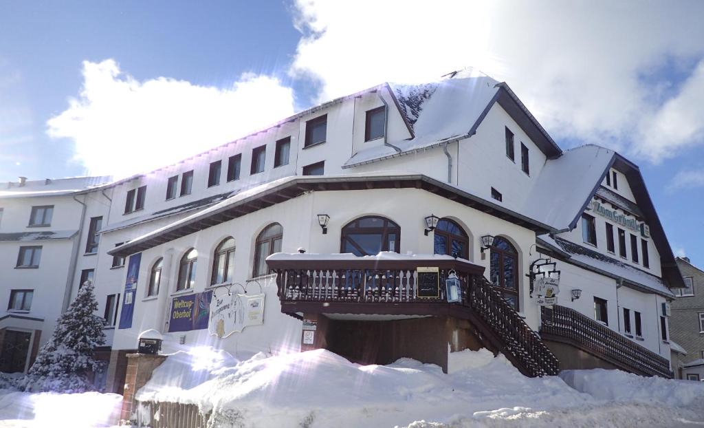 a large white building with a balcony in the snow at Hotel Zum Gründle in Oberhof