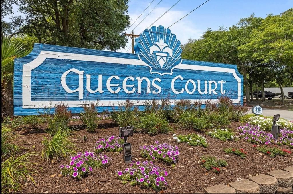 a sign for a queens court with flowers in a garden at Mystic Sands in Emerald Isle