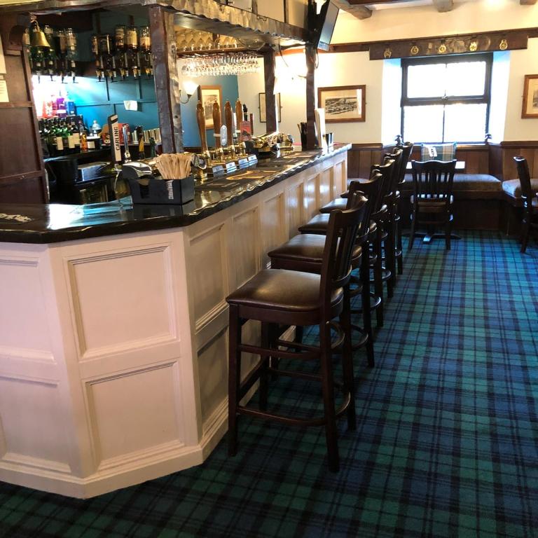 a bar with a row of stools in a restaurant at The Cottage Inn in Craster