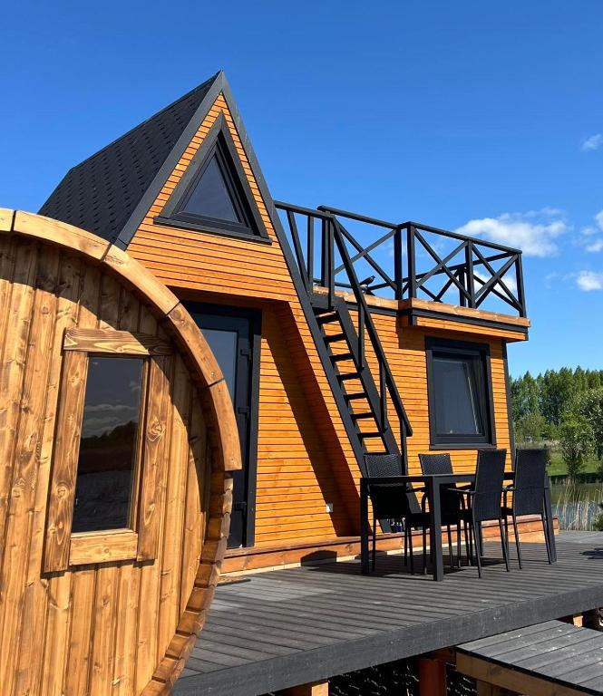 a wooden cabin with a table and chairs on a deck at Liepų namelis - Linden Shore in Miroslavas