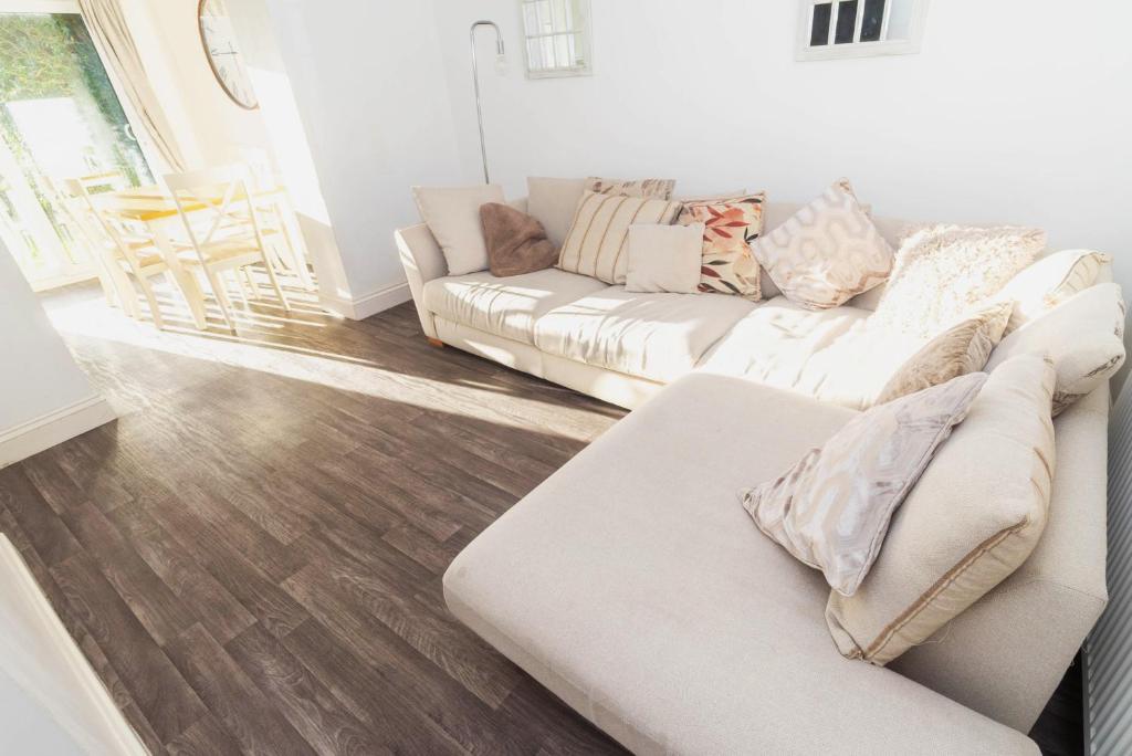 a living room with a white couch and wooden floors at Glenroy House Swansea in Swansea