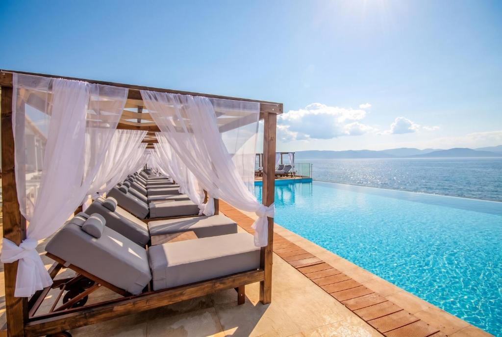 a bed on the edge of a pool with the ocean at Alyssium in Benitses