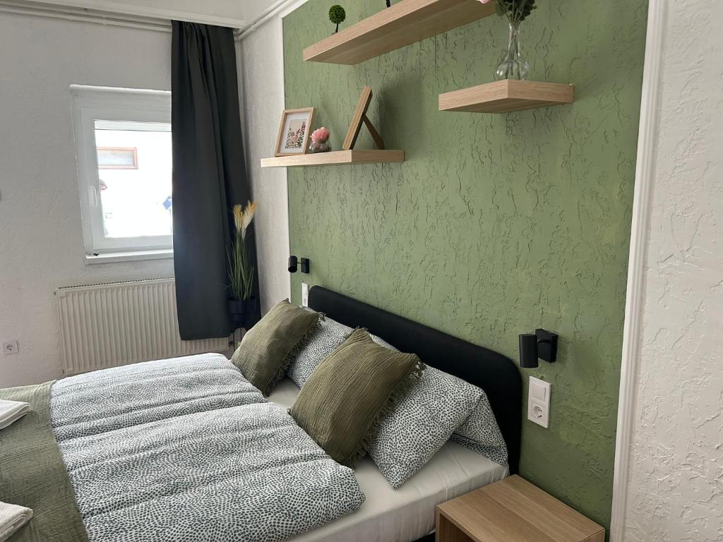 a bedroom with a bed and a green wall at Balaton Bloom 24 in Siófok