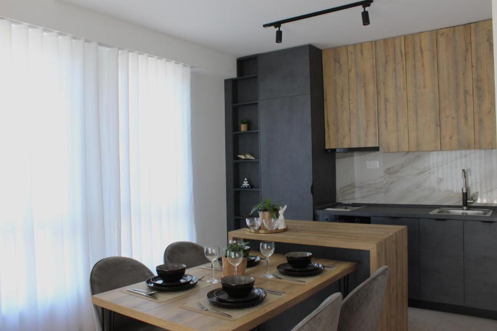 a kitchen with a wooden table with chairs and a dining room at Hug and Fly Apartment in Skopje