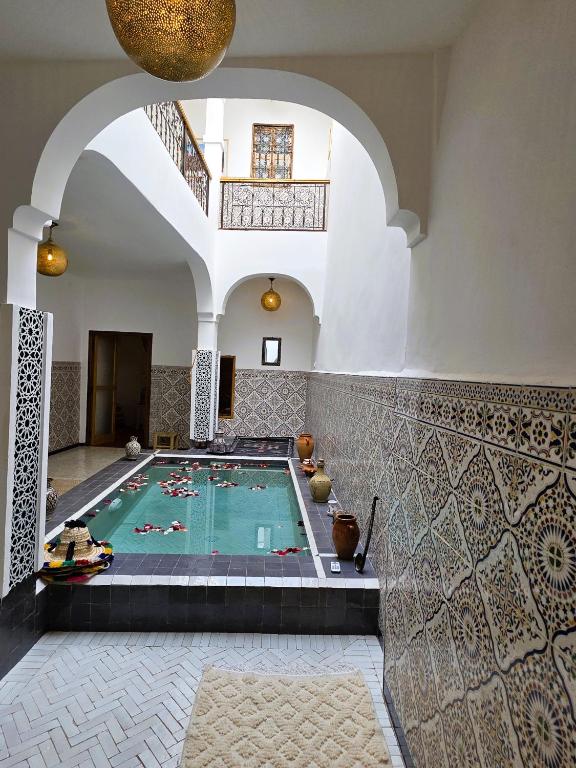 a swimming pool in a building with an archway at Riad Patio des Amis Marrakech in Marrakesh