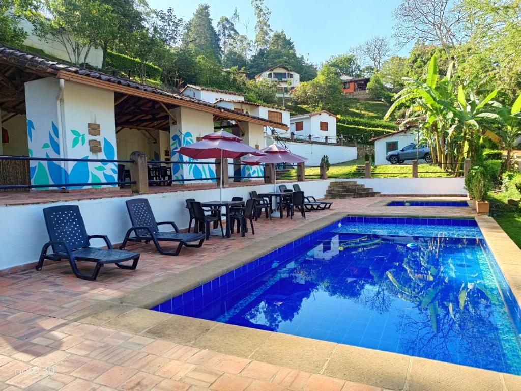 a pool with chairs and tables next to a house at Aires de Encanto in Curití