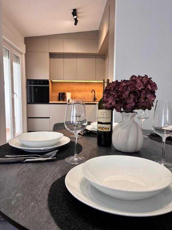 a table with plates and glasses and a bottle of wine at Apartments Šebin in Baška Voda