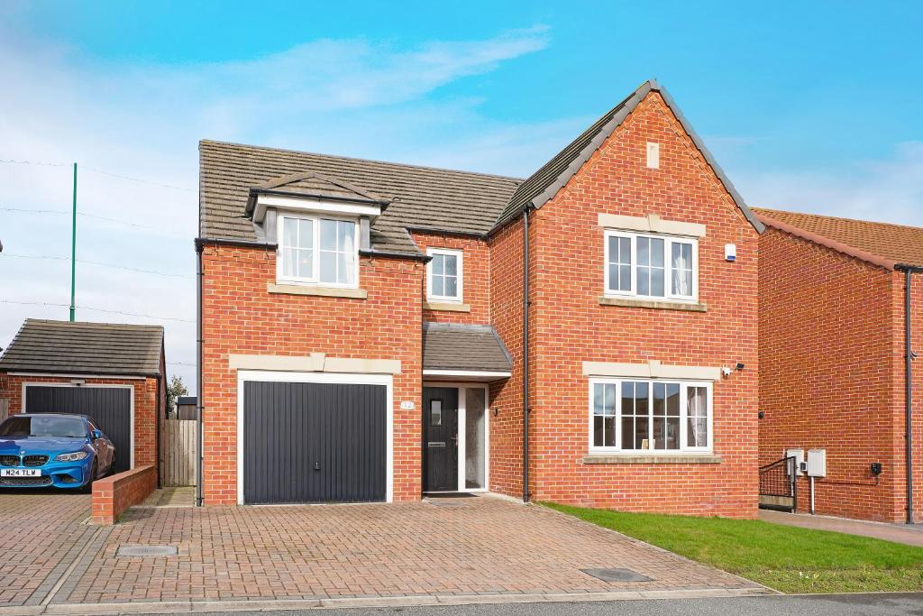 a brick house with a car parked in the driveway at Folly Lodge in Barnsley