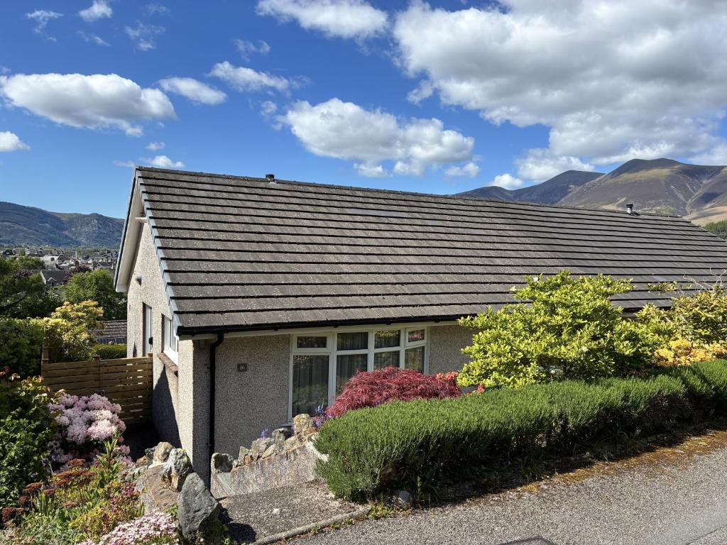 a small white house with mountains in the background at 16 Manesty View in Keswick