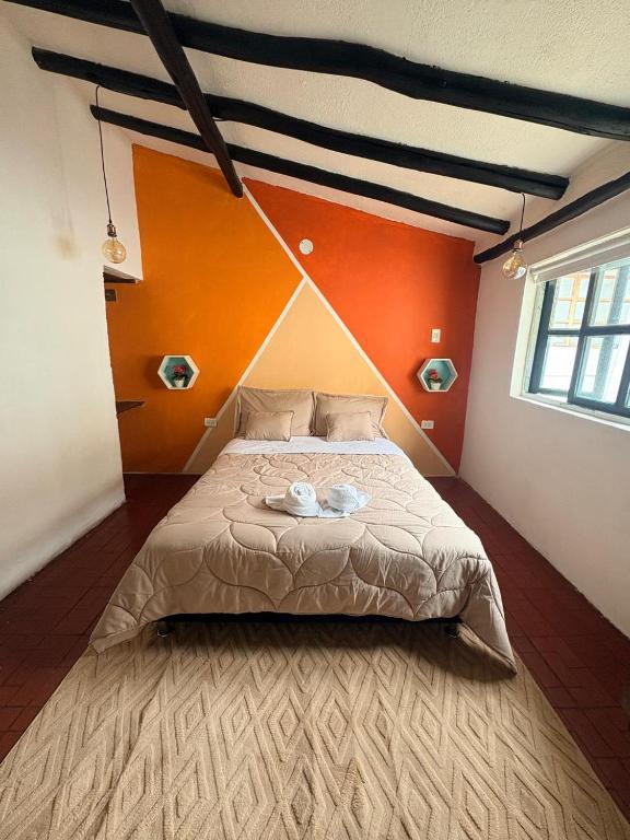 a bedroom with a large bed with an orange wall at Hotel Alma Divina in Villa de Leyva