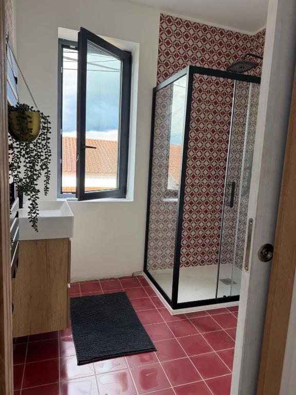 a bathroom with a shower with a window and red tiles at Casa Albertina in Mogofores