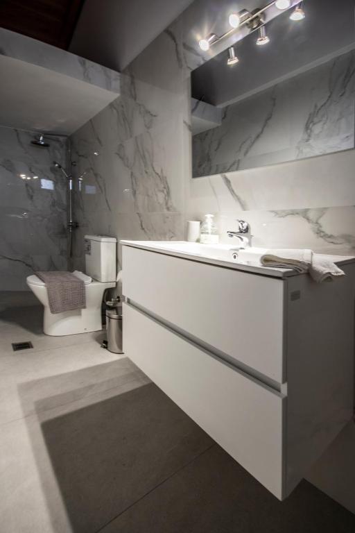 a white bathroom with a sink and a toilet at Αριάδνη in Archanes