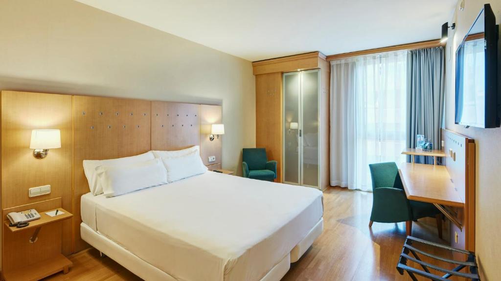 a hotel room with a large bed and a desk at Sercotel Porta Barcelona in Sant Just Desvern