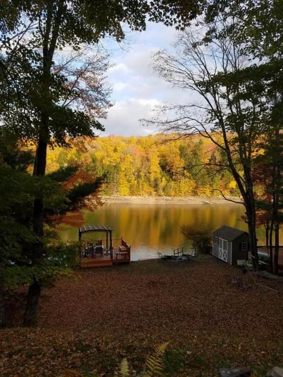 a view of a lake with a house and a dock at Fun 5 Bedroom Lakefront Cottage in Bethel