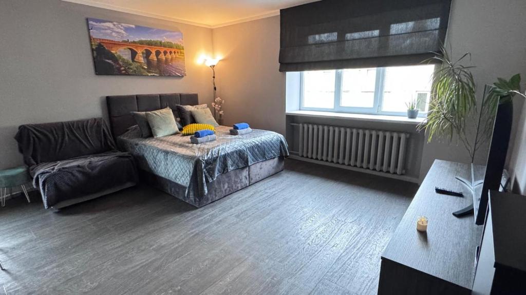 a bedroom with a bed and a couch and a window at Mucenieku Apartamenti in Kuldīga