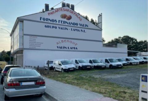 a parking lot with cars parked in front of a building at ALBERGUE VALIN LAMA in Palas de Rei