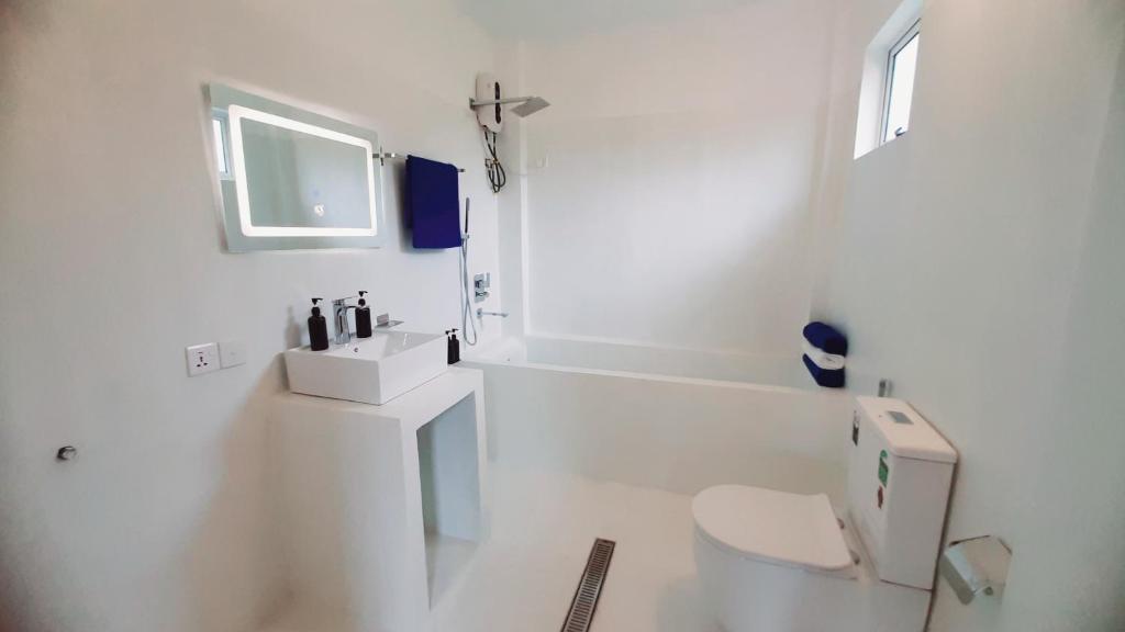 a white bathroom with a toilet and a sink at Anchor House in Ahangama