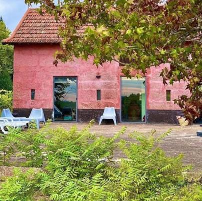 a red building with tables and chairs in front of it at Casa de Cabanelas in Bustelo
