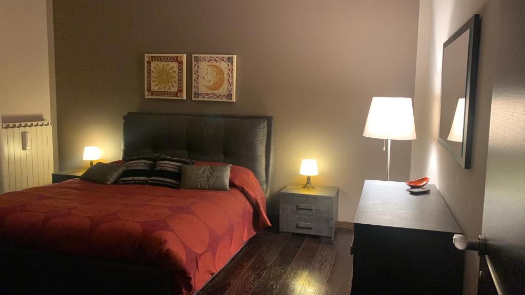 a bedroom with a bed with a red comforter and two lamps at Casa Bea in Fasano