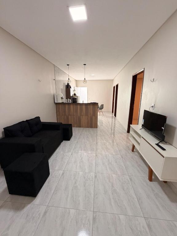 a living room with a black couch and a piano at Comfort Ton House in Juazeiro do Norte