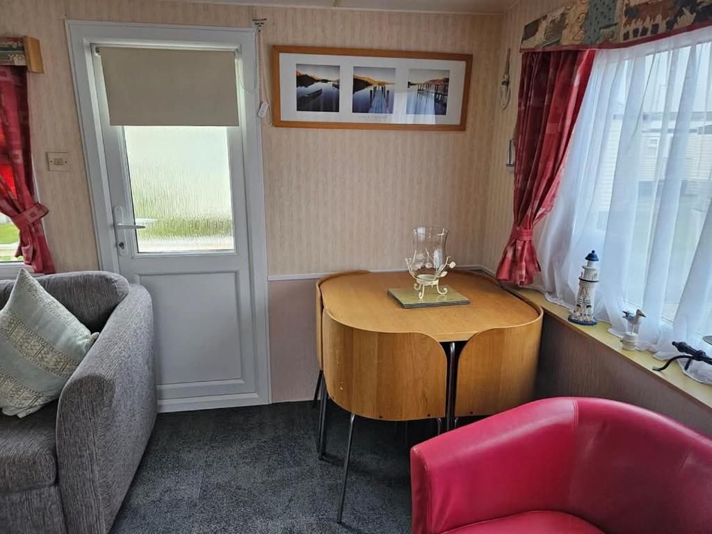 a living room with a table and a chair at Home from home 2 in Ingoldmells